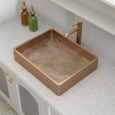 a bathroom sink sitting on top of a white counter next to a green bottle and soap dispenser