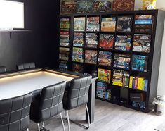 a dining room table with four chairs and a book shelf filled with games on it