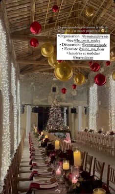 a long table set up with christmas decorations and candles in front of a large tree