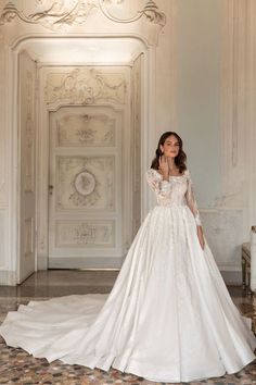 a woman in a white wedding dress standing on the floor next to a wall and doorway