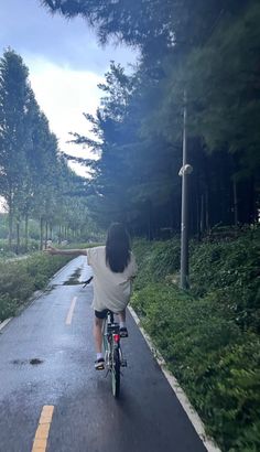 a person riding a bike down the middle of a road with trees in the background