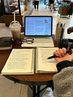 a person sitting at a table with a laptop and notebook