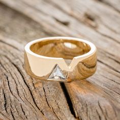 a gold ring with a diamond on it sitting on top of a piece of wood