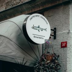 a sign on the side of a building with a fish hanging from it's side