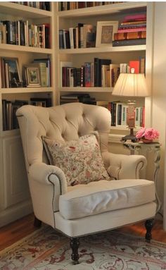 a white chair sitting in front of a book shelf filled with books