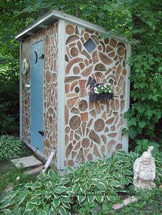 a stone outhouse in the woods with plants around it