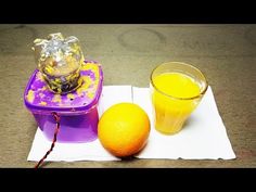 an orange sitting on top of a table next to a juicer and glass filled with liquid