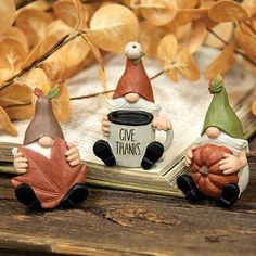 three gnome figurines sitting on top of an open book with the words give thanks