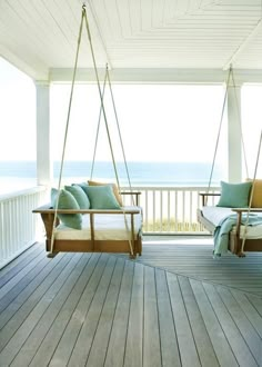 a porch with two swing chairs on it and the ocean in the backround