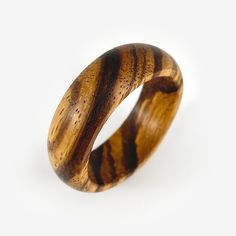 The Round Band ring handmade from solid zebrawood. Made to your ring size when you order, other woods available upon request. The round band gives this ring design a classic feel while allowing the unique woodgrain and the texture of the zebrawood to become the main focus (also called zebrano wood). Though understated, these wood rings are thoughtfully made in a slow hands-on process, no lathe, no CNC machining. I think the care that goes into making these by hand can be felt, even if it isn't apparent at first glance. What you see pictured are pieces I have made and represent what you are ordering. However, your ring will be unique to you and may vary slightly in color and grain pattern. Wood is a natural material, each piece is different and should be enjoyed for its individuality. ◆ Con Minimalist Brown Rings For Gifts, Handmade Round Wooden Jewelry, Round Brown Wooden Jewelry, Brown Round Wooden Jewelry, Mens Wood Rings, Slow Hands, Wooden Rings Engagement, Wooden Wedding Ring, Bentwood Rings