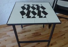 a table with black and white tiles on it in the middle of a wooden floor