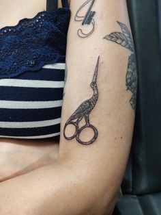 a woman with a tattoo on her arm holding scissors