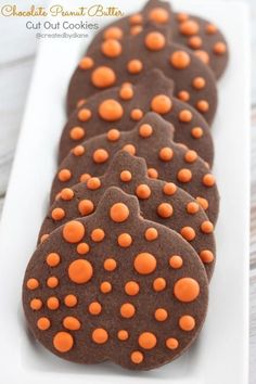 chocolate cookies with orange polka dots on a white plate