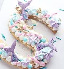 there is a number made out of cookies with mermaid decorations on it and sprinkles