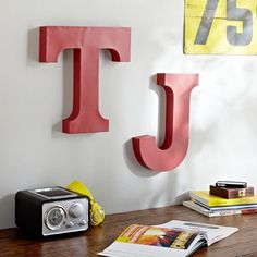 a wooden table topped with a radio next to a wall mounted letter j and t