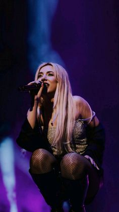 lady in fishnet stockings on stage holding a microphone and looking into the distance with her legs crossed