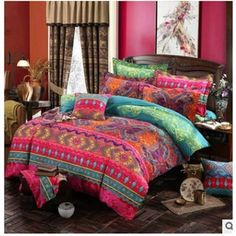 a bed room with a neatly made bed covered in colorful comforter and pillows on the floor