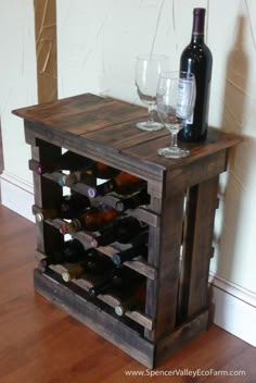 a wooden table with wine bottles and glasses on it, next to a glass holder