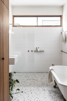 a white bath tub sitting under a window next to a sink