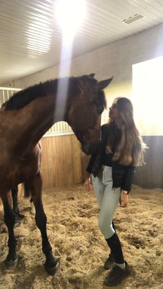 a woman standing next to a brown horse