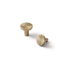 two brass knobs on white background with shadows in the foreground, one has a circular design