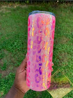 a hand holding up a pink and purple tumbler