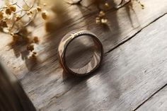 a wooden ring sitting on top of a table next to some dried flowers and branches