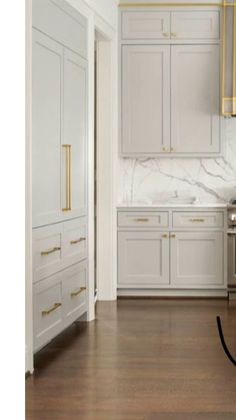 a kitchen with marble counter tops and white cabinets, gold trimming on the doors