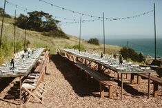 a long table set up on the side of a hill with lights strung over it