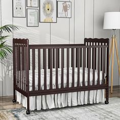 a baby crib with white bedding and pictures on the wall in front of it