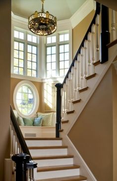 there is a stair case in front of the window on the second floor, and an oval window at the top of the stairs