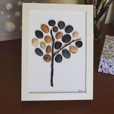 a white frame with a tree made out of rocks on top of a wooden table