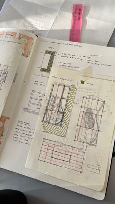 an open book with drawings on it and a ruler next to it that is sitting on top of a table