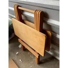 a wooden chair sitting on top of a floor next to a cement wall with pieces of wood sticking out of it