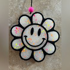 a white and black flower ornament hanging from a hook on the ground with sprinkles all over it