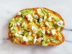 an avocado and feta sandwich on a marble surface