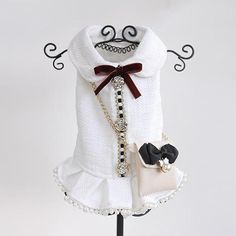 a white sweater with black and red bows is on a display stand holding a purse