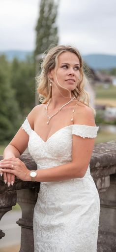 a woman in a white dress leaning on a fence