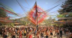 a large group of people standing around each other in front of a giant kite that looks like it has been blown by the wind