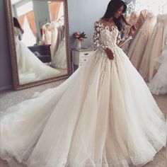 a woman standing in front of a mirror wearing a wedding dress