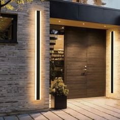 a modern entrance to a house with brick walls and doors lit up by led lights