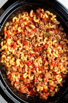 a crock pot filled with macaroni and cheese, meat sauce and onions