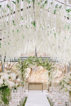 an outdoor ceremony setup with white flowers and greenery on the aisle, surrounded by chairs