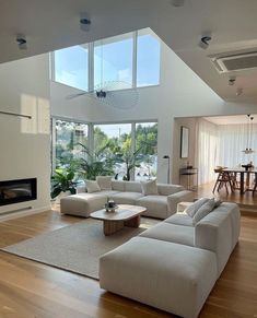 a modern living room with high ceilings and large windows on the wall, along with hardwood flooring