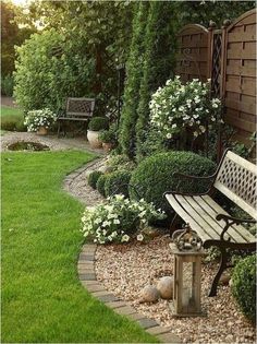 a wooden bench sitting in the middle of a lush green yard with white flowers and greenery