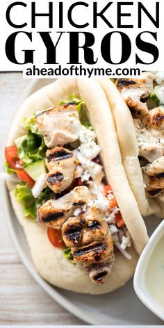 two chicken gyros with lettuce, tomatoes and onions on a plate