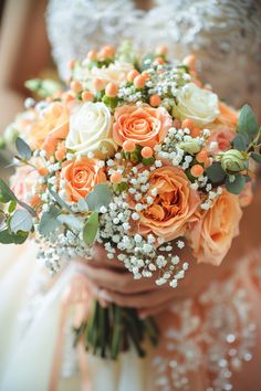 a bridal holding a bouquet of orange and white flowers with baby's breath