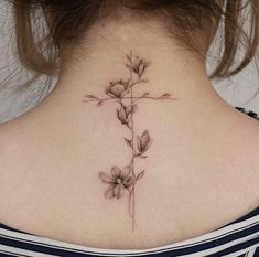 a woman's back neck with a cross and flowers tattoo on her left side