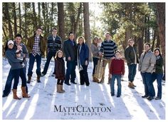 a group of people standing next to each other in the snow with trees behind them