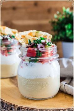 two jars filled with food sitting on top of a wooden table